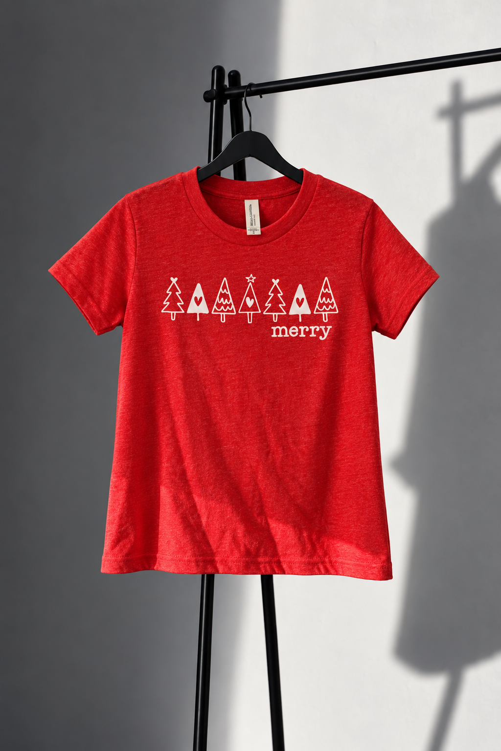 Red Bella Canvas youth tee with seven white Christmas trees and merry lettering