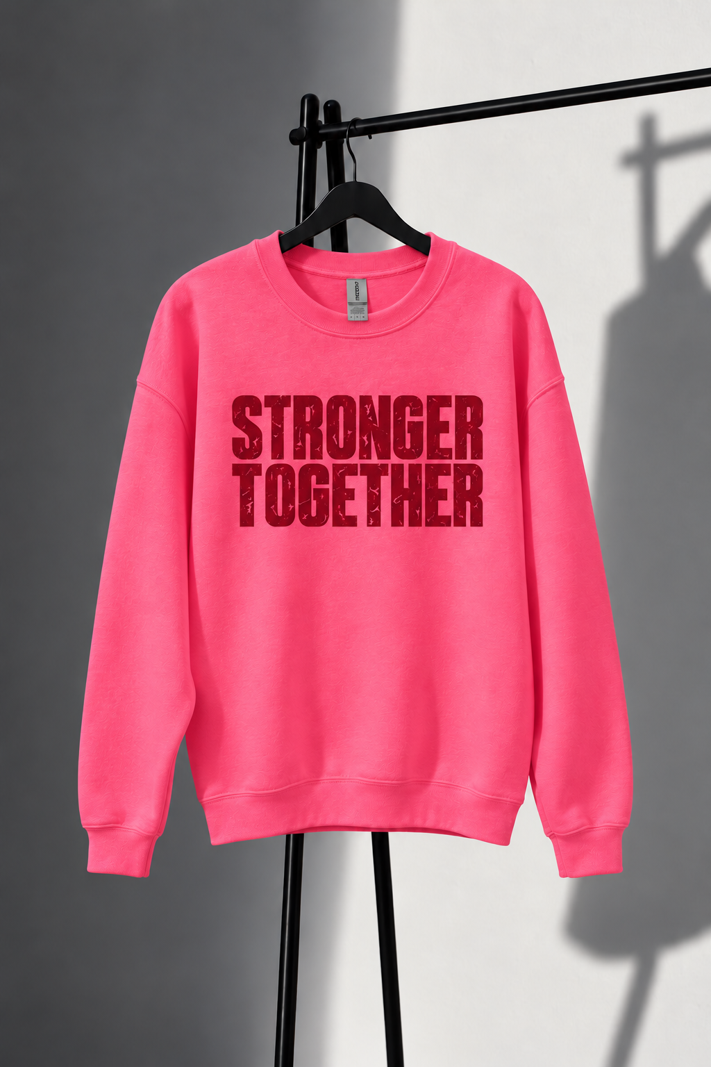 Neon pink Stronger Together sweatshirt with straight horizontal lettering on black studio rack